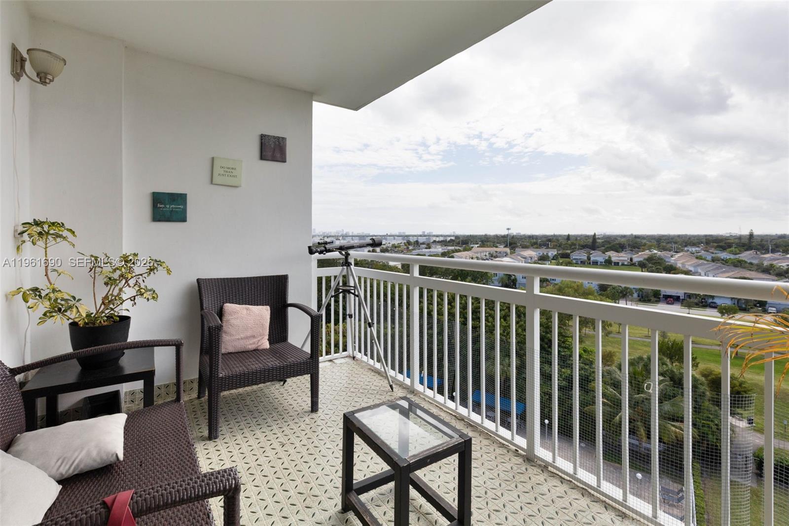 A balcony features wicker furniture, a telescope, and a view of suburban houses and trees — 4400 Hillcrest Dr # 901B, Hollywood FL 33021, HOLLYWOOD, FL