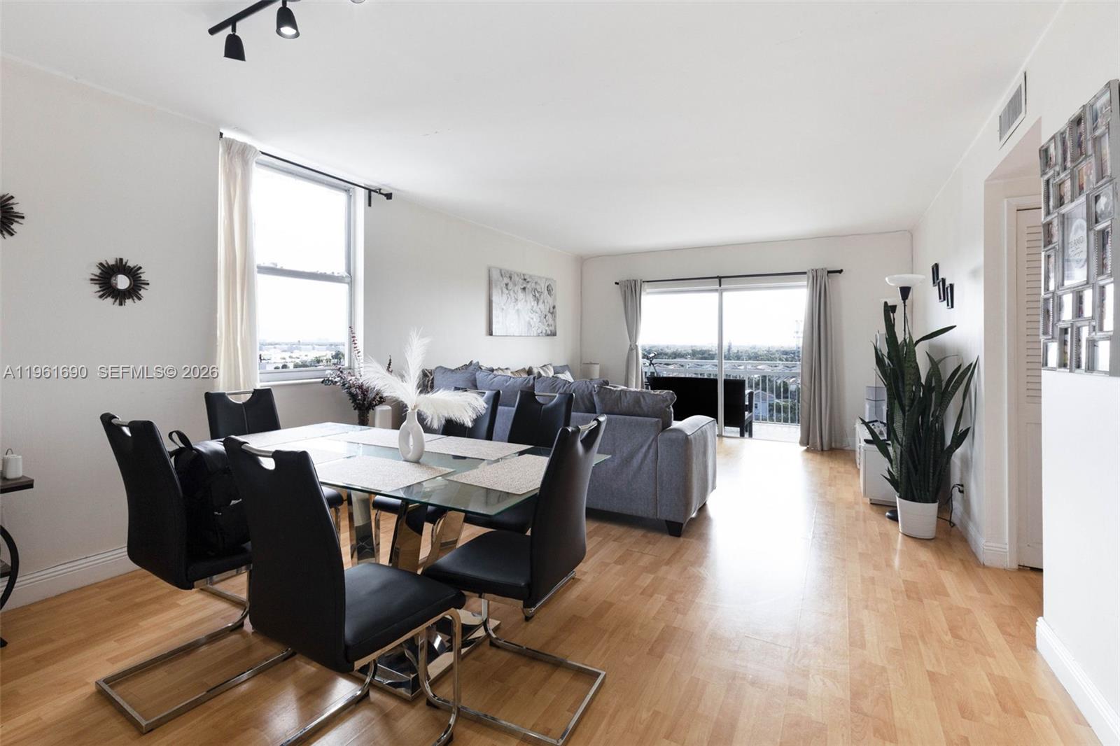 A dining area with a glass table and black chairs opens into a living room — 4400 Hillcrest Dr # 901B, Hollywood FL 33021, HOLLYWOOD, FL