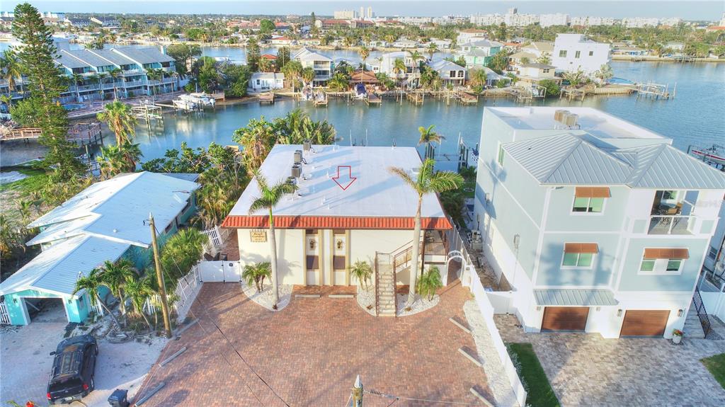 An aerial view shows a coastal property with a white-roofed building and private boat docks — 8535 BLIND PASS DRIVE UNIT 103, TREASURE ISLAND, FL