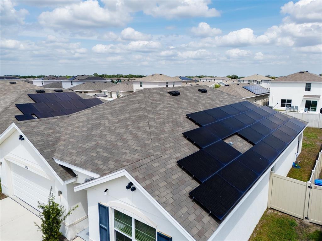 An aerial view of a residential roof featuring multiple solar panel arrays — 16742 SUNBURST LAKE STREET, WIMAUMA, FL