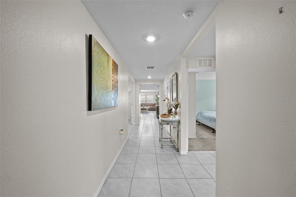 A tiled hallway leads past a console table and bedroom toward a living area — 16742 SUNBURST LAKE STREET, WIMAUMA, FL