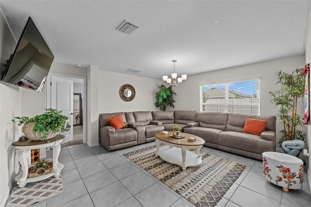 A living room features a large sectional sofa, a coffee table, and tile flooring — 16742 SUNBURST LAKE STREET, WIMAUMA, FL