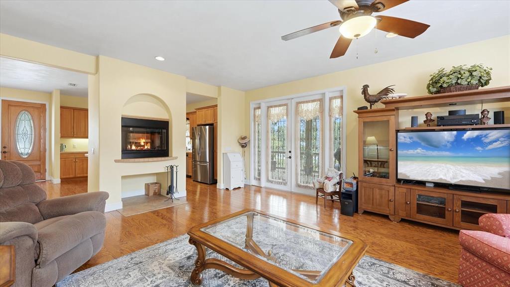A living room with a fireplace, hardwood floors, a ceiling fan, and an entertainment center — 280 W COWLES STREET, ENGLEWOOD, FL