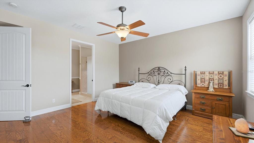 A bedroom features hardwood floors, a white bed with a metal frame, and a ceiling fan — 280 W COWLES STREET, ENGLEWOOD, FL