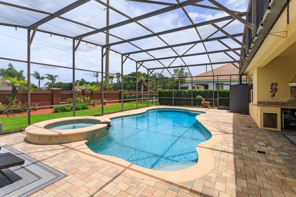 A screened-in patio features a swimming pool, a raised spa, and an outdoor kitchen area — 2759 MARIA ISABEL AVENUE, OCOEE, FL