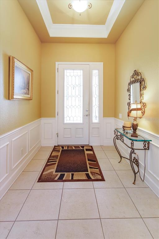 A foyer features tile flooring, wainscoting, a tray ceiling, and a glass-paneled front door — 2759 MARIA ISABEL AVENUE, OCOEE, FL