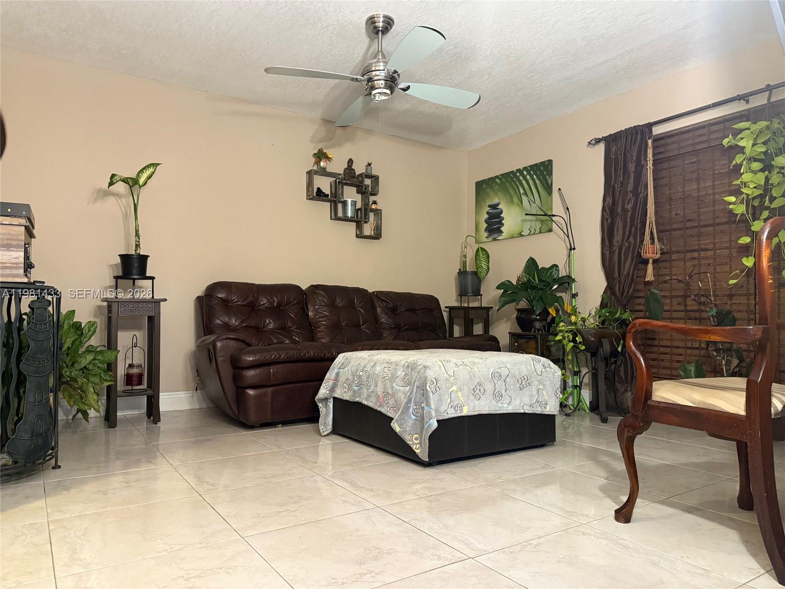 A living room features a brown leather sofa, tiled floors, and a ceiling fan — 5119 SW 153rd Pl N, Miami FL 33185, MIAMI, FL