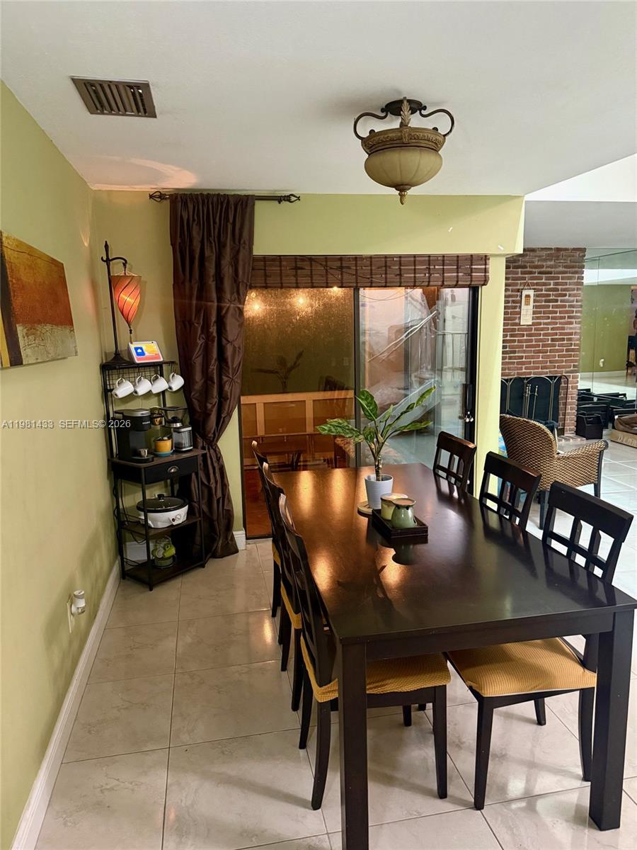A dining room features a dark wood table, matching chairs, and a sliding glass door — 5119 SW 153rd Pl N, Miami FL 33185, MIAMI, FL