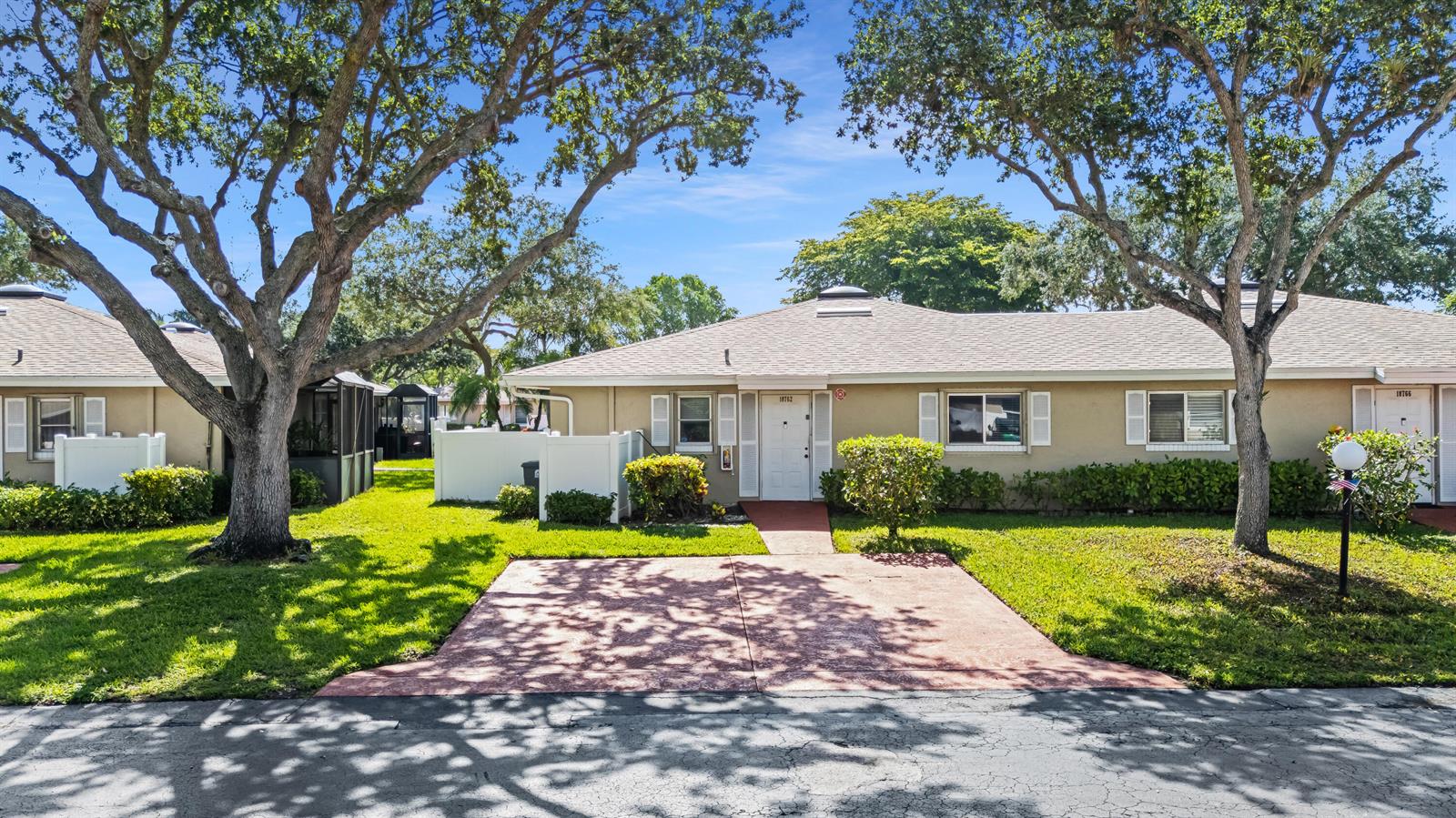 A single-story tan villa with a red concrete driveway and mature trees in the front — 18762 Candlewick Drive, Boca Raton FL 33496, BOCA RATON, FL