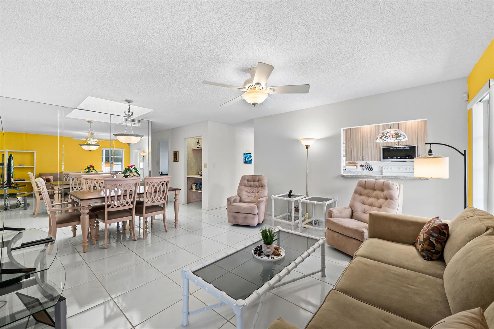 A living and dining room with white tile floors, a ceiling fan, and yellow walls — 18762 Candlewick Drive, Boca Raton FL 33496, BOCA RATON, FL
