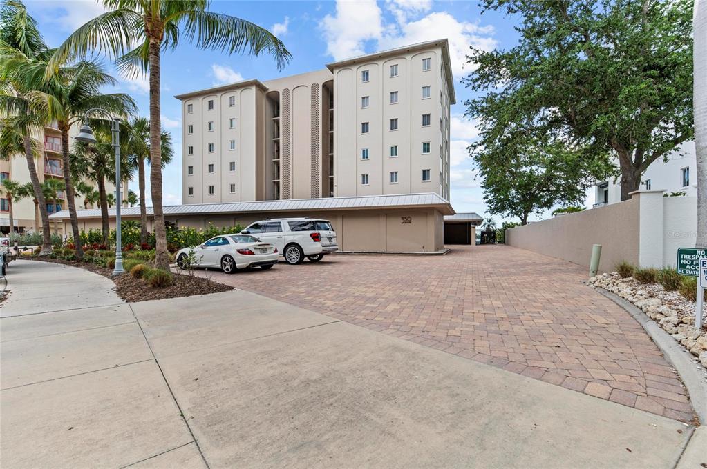 A multi-story beige apartment building with a paved parking area and palm trees — 350 GOLDEN GATE POINT UNIT 61, SARASOTA, FL