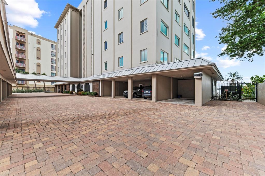 An exterior view of a multi-story building with a paved parking area and covered spaces — 350 GOLDEN GATE POINT UNIT 61, SARASOTA, FL