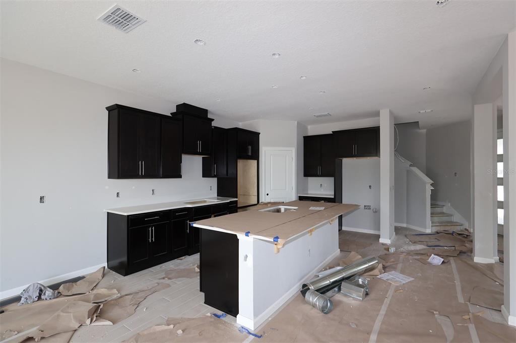 A kitchen with dark cabinets, a large island, and light wood-look flooring — 2685 GREAT HERON AVENUE, ST CLOUD, FL