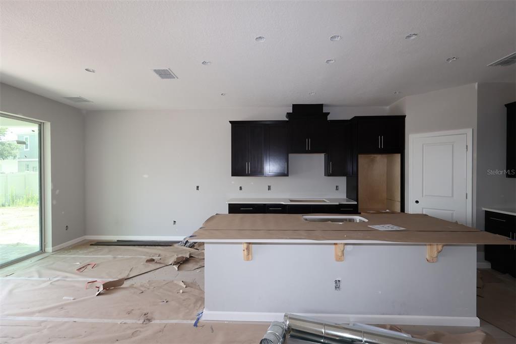 A kitchen features dark cabinetry, a large white quartz island, and light tile flooring — 2685 GREAT HERON AVENUE, ST CLOUD, FL