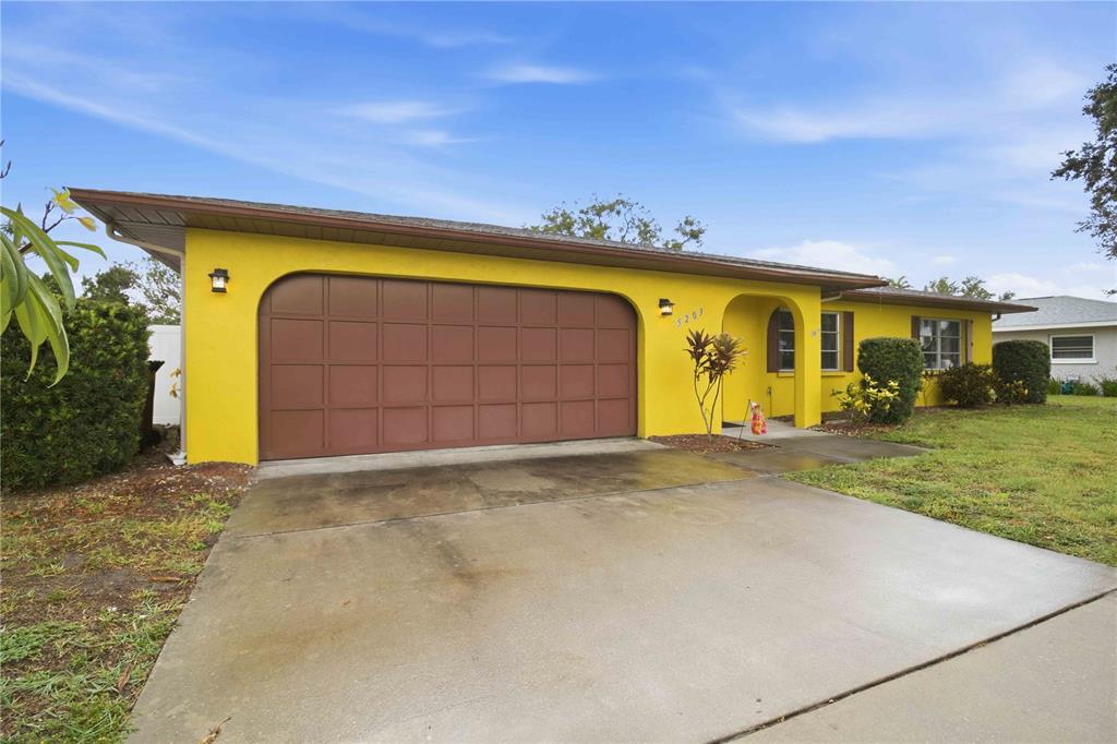 A single-story house with bright yellow exterior walls, a brown garage door, and a driveway — 5203 18TH AVENUE W, BRADENTON, FL