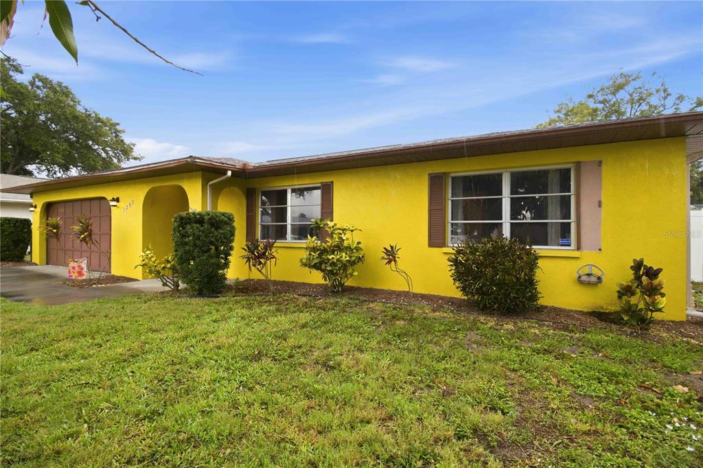 A single-story house with bright yellow exterior walls, a brown garage door, and brown shutters — 5203 18TH AVENUE W, BRADENTON, FL