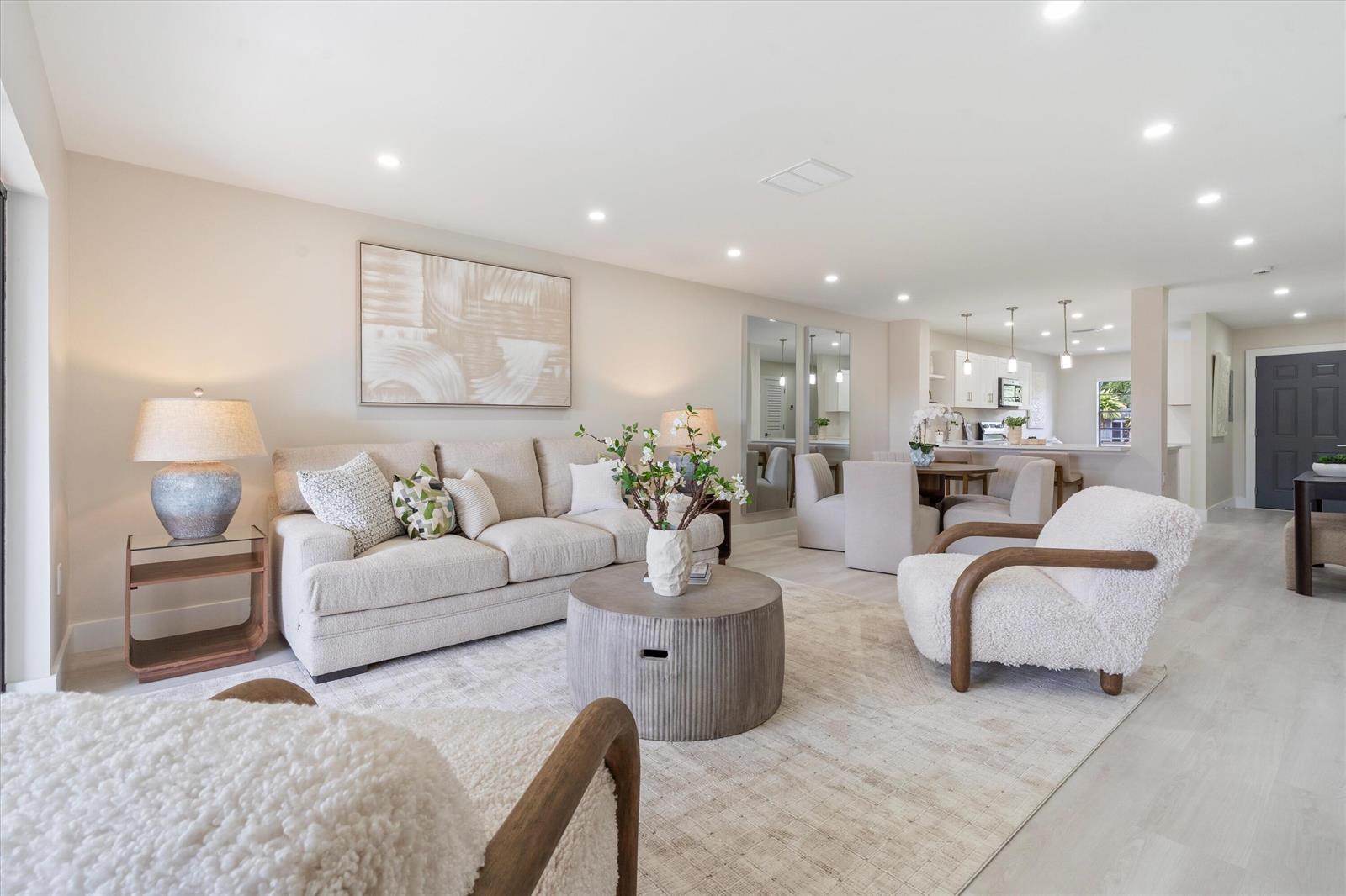 A bright living room features a beige sofa, two textured armchairs, and an open kitchen — 47 Stratford Lane W # F, Boynton Beach FL 33436, BOYNTON BEACH, FL