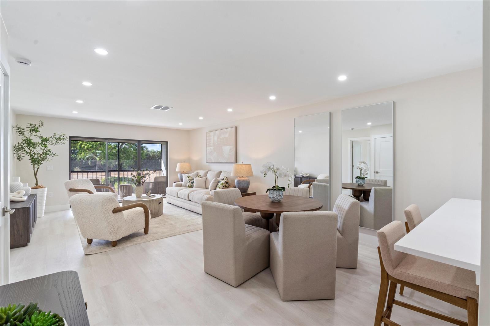 A bright, open-concept living and dining area features light wood floors and neutral furniture — 47 Stratford Lane W # F, Boynton Beach FL 33436, BOYNTON BEACH, FL