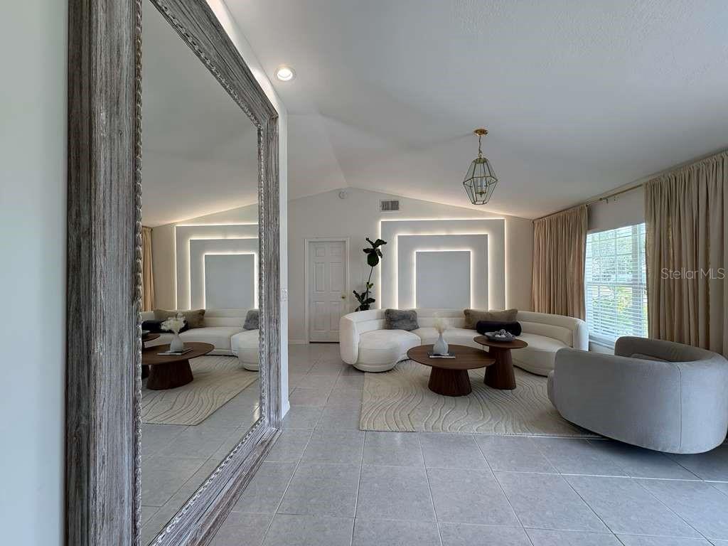 A living room features a large floor mirror, a curved sectional sofa, and backlit wall panels — 605 TAMARIN LANE, KISSIMMEE, FL
