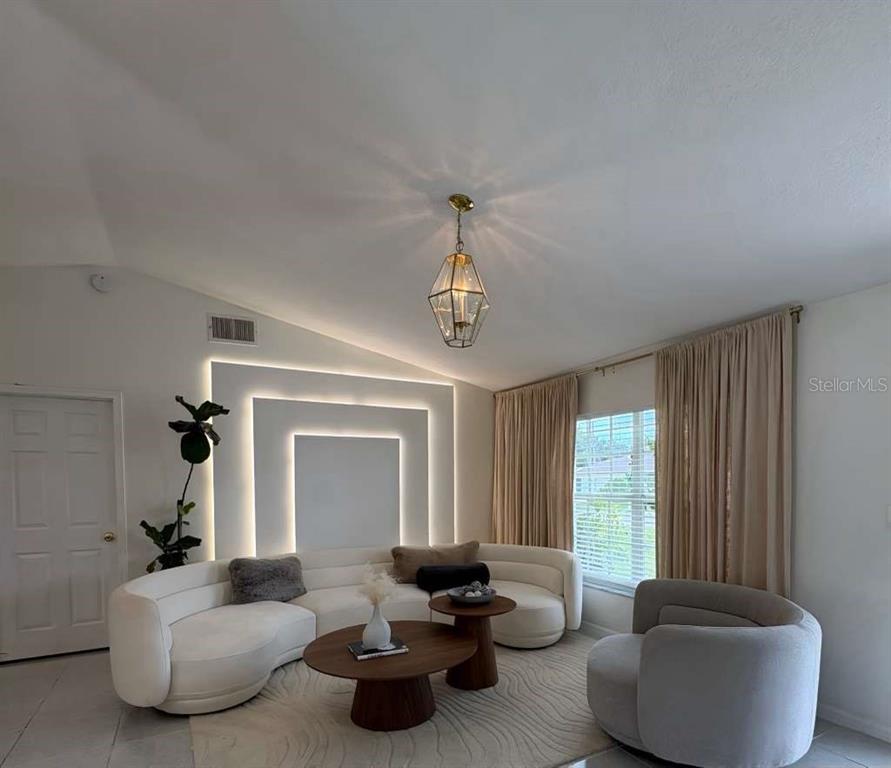 A living room features a curved white sofa, a round wooden coffee table, and backlit wall panels — 605 TAMARIN LANE, KISSIMMEE, FL