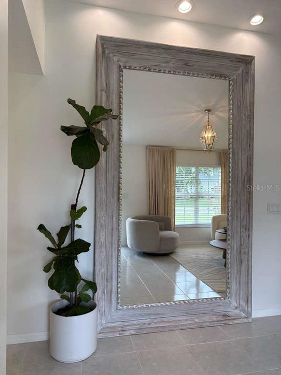 A large floor mirror with a weathered wood frame stands beside a potted fiddle-leaf fig — 605 TAMARIN LANE, KISSIMMEE, FL