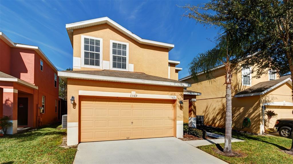 A two-story house with a tan stucco exterior and a two-car garage — 1369 ROYAL RIDGE DRIVE, DAVENPORT, FL