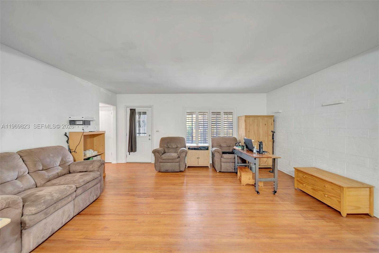 A living room features light wood flooring, white walls, a sofa, two armchairs, and a desk — 890 NE 138th St, North Miami FL 33161, NORTH MIAMI, FL