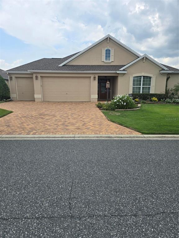 A single-story house with a beige stucco exterior, a brick paver driveway, and a garage — 3452 BOSIE RUN, THE VILLAGES, FL