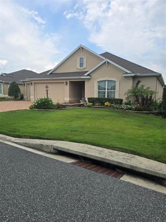 A tan, single-story house with a two-car garage and a landscaped front yard — 3452 BOSIE RUN, THE VILLAGES, FL