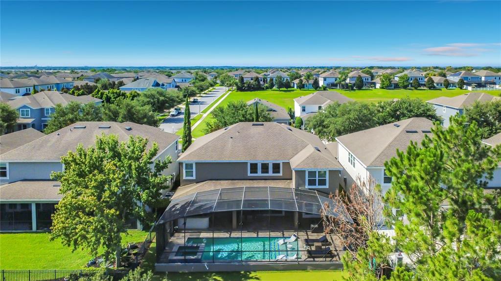 A screened-in pool and spa area with stone decking overlooking a sunset landscape — 14591 BLACK QUILL DRIVE, WINTER GARDEN, FL