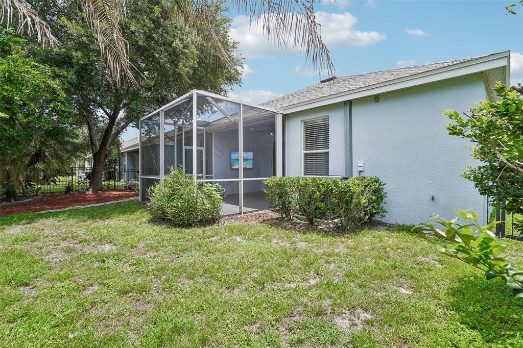 A backyard view showing a house with a screened-in patio and a grassy lawn — 6111 GANNETSIDE PLACE, LITHIA, FL