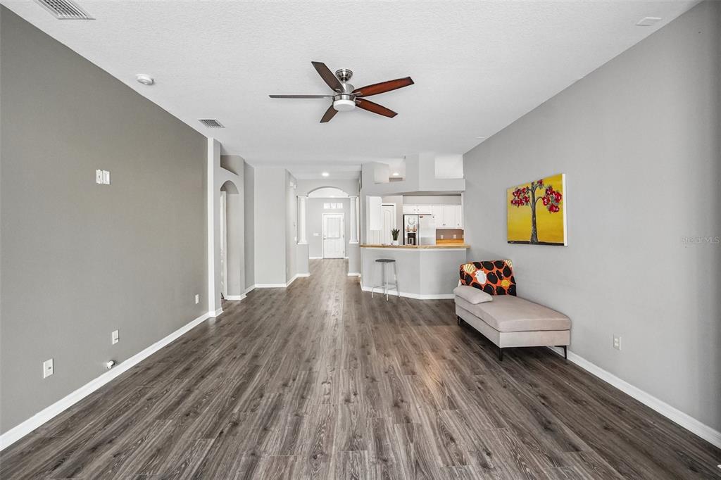 A living room with gray walls, wood-look flooring, a ceiling fan, and a chaise lounge — 6111 GANNETSIDE PLACE, LITHIA, FL
