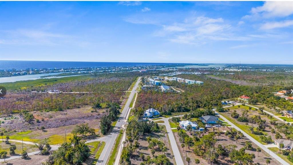 An aerial view shows a road running through a coastal landscape with scattered houses and vegetation — 60 BONITA STREET, PLACIDA, FL