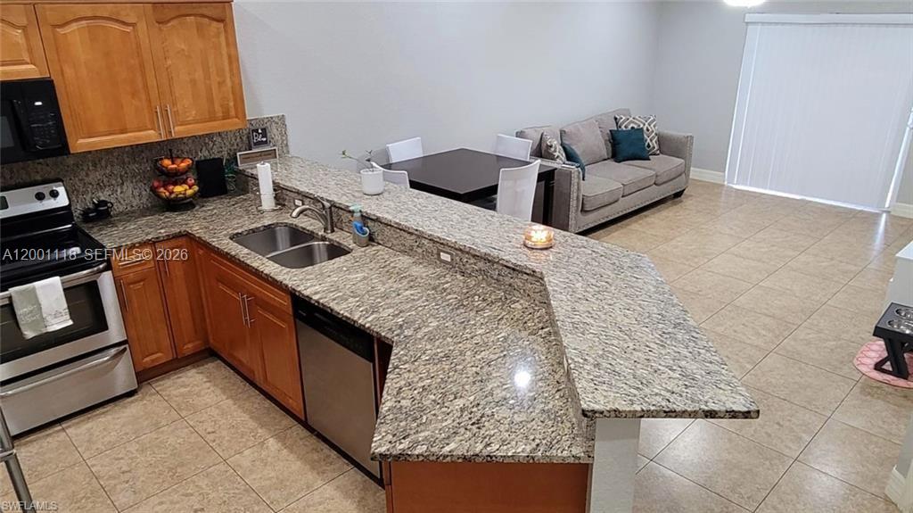 A kitchen with wood cabinets and granite countertops overlooks a dining area and living room — 152 Pullman St # 152, Lehigh Acres FL 33974, LEHIGH ACRES, FL