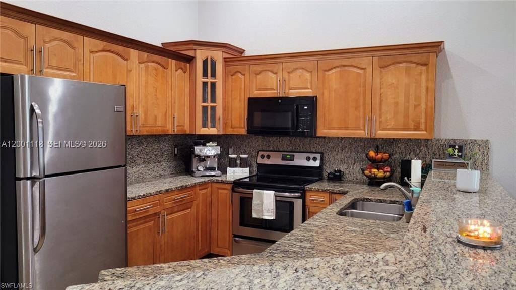 A kitchen features wood cabinets, granite countertops, and stainless steel appliances — 152 Pullman St # 152, Lehigh Acres FL 33974, LEHIGH ACRES, FL