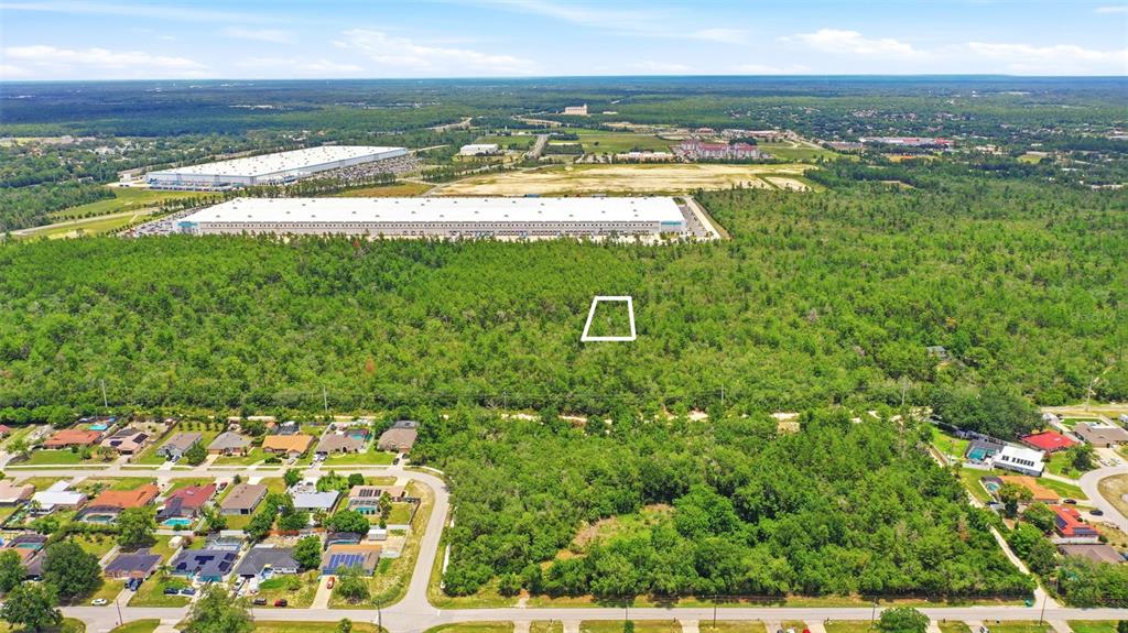 An aerial view shows a wooded lot marked with a white square near industrial warehouses — EDGEMONT (PAPER) AVENUE, DELTONA, FL