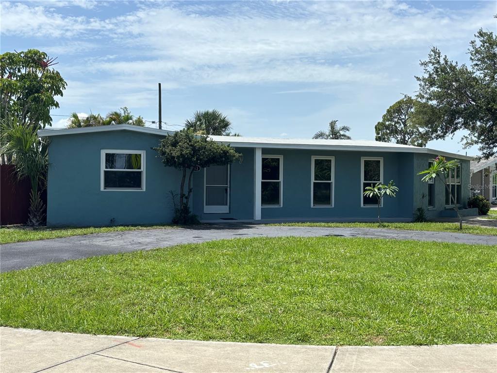 A single-story blue house with a flat roof and a paved driveway sits on grass — 2513 AMBROSE LANE, PORT CHARLOTTE, FL