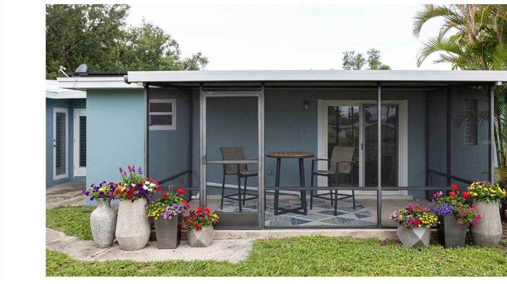 A screened-in patio features a small table, two chairs, and several potted flower arrangements — 2513 AMBROSE LANE, PORT CHARLOTTE, FL