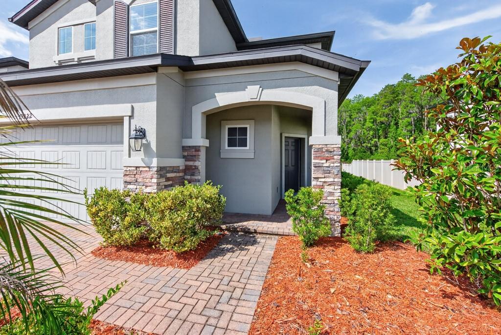 A paved walkway leads to the covered entryway of a two-story house with stone accents — 19222 OLD SPANISH ROAD, TAMPA, FL