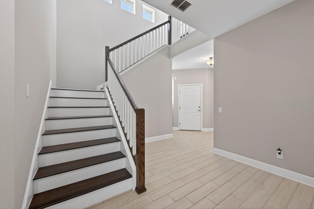 A foyer features a staircase with dark wood treads and white risers and tile flooring — 19222 OLD SPANISH ROAD, TAMPA, FL