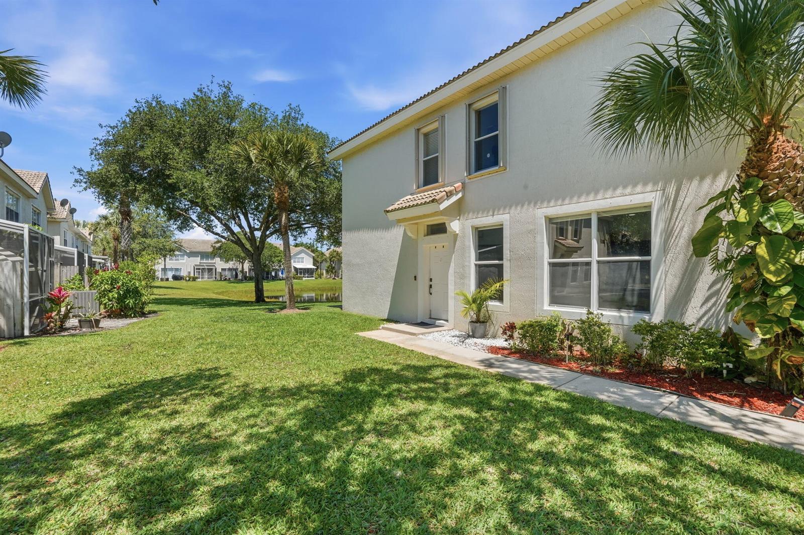 A two-story stucco house exterior features a front entrance, walkway, and a grassy yard — 1086 Woodfield Road, FL 33415, FL