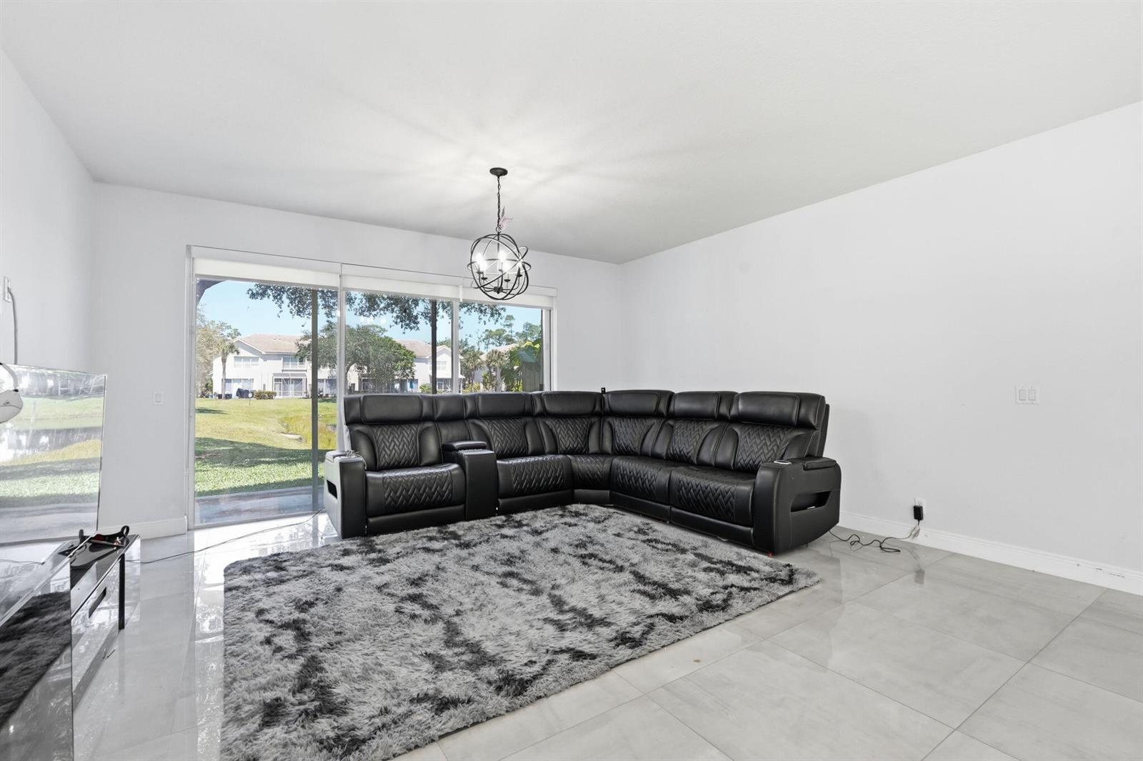 A living room features a black leather sectional, a shaggy rug, and sliding glass doors — 1086 Woodfield Road, FL 33415, FL