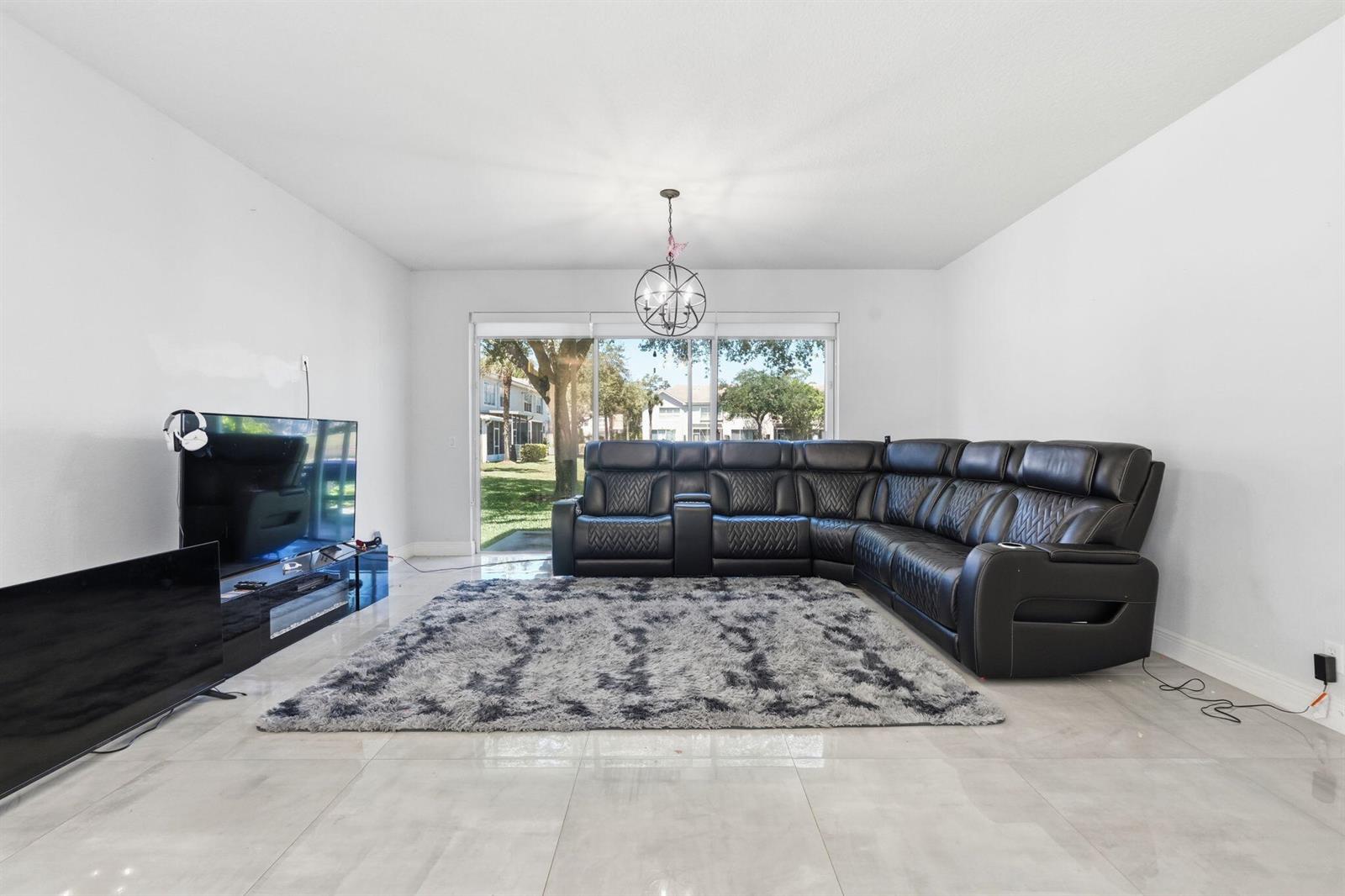 A living room features a black sectional sofa, a gray shag rug, and a television — 1086 Woodfield Road, FL 33415, FL