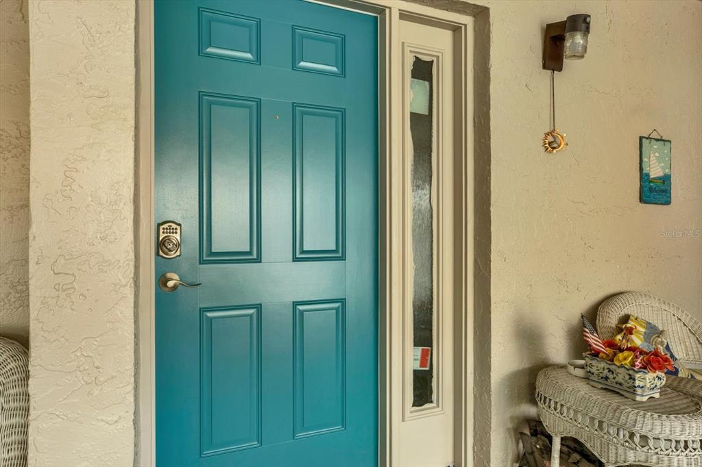 A teal front door with a sidelight is situated on a covered porch — 1204 11TH CIRCLE SE, LARGO, FL