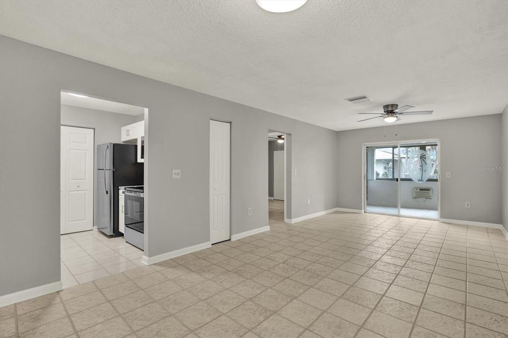 A living room with light tile flooring, gray walls, and a sliding glass door — 1204 11TH CIRCLE SE, LARGO, FL