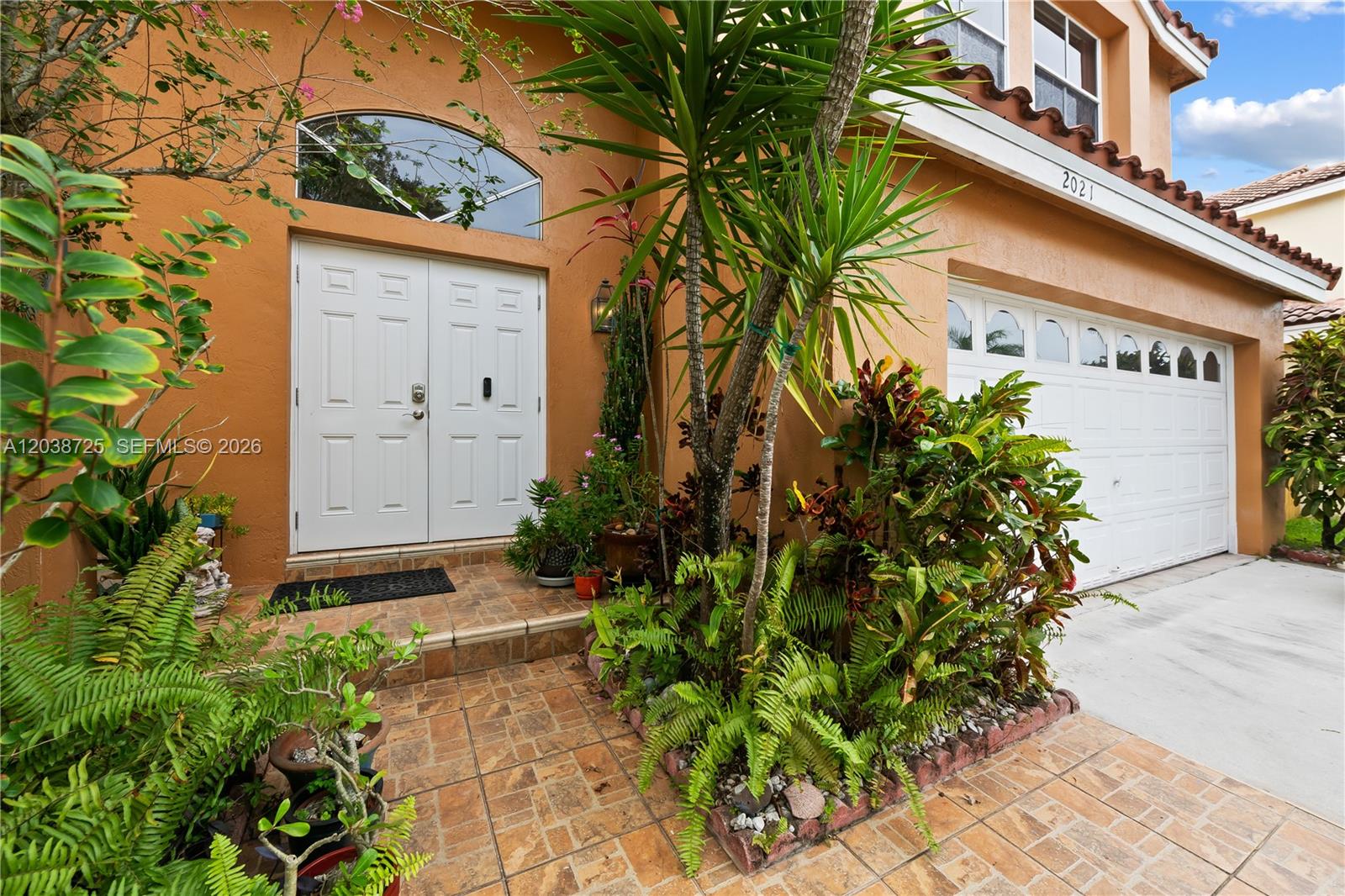 The exterior of a house features a double front door, a garage, and lush landscaping — 2021 Barcelona Ter, Margate FL 33063, MARGATE, FL