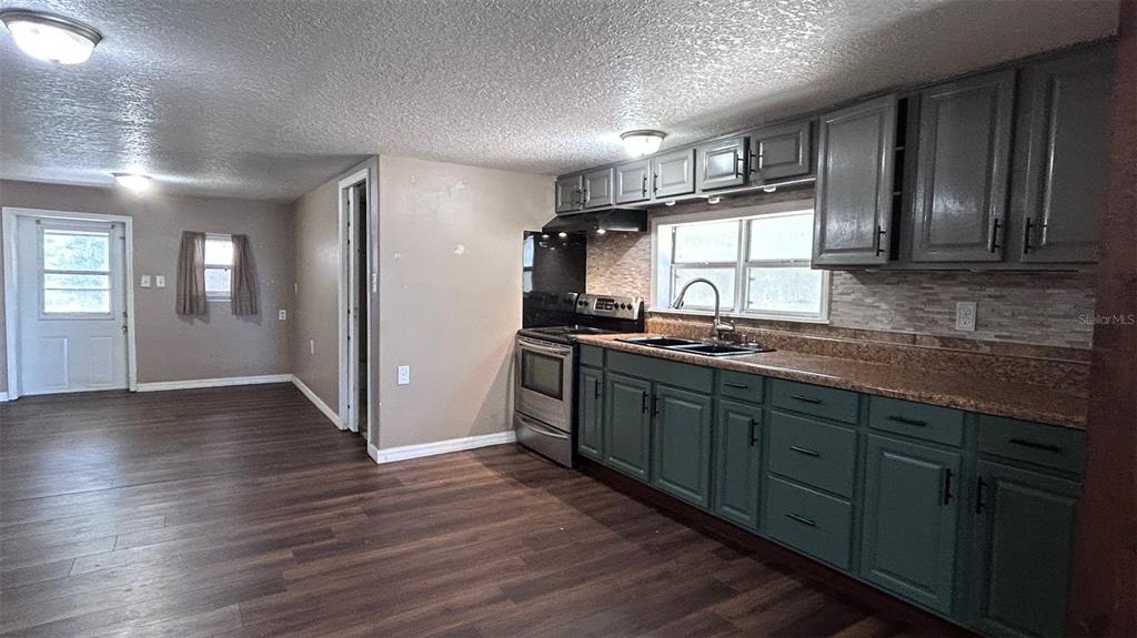 A kitchen features green lower cabinets, grey upper cabinets, and wood-look flooring — 4800 PETROFF AVENUE, ORLANDO, FL