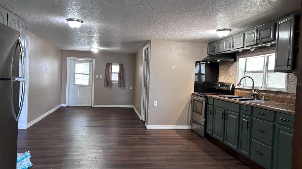A kitchen with dark green cabinets, stainless steel appliances, and wood-look flooring — 4800 PETROFF AVENUE, ORLANDO, FL