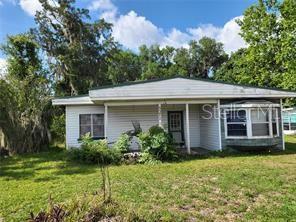 A single-story house with white horizontal siding, a front porch, and a bay window — 5371 WARM SPRINGS AVENUE, WILDWOOD, FL