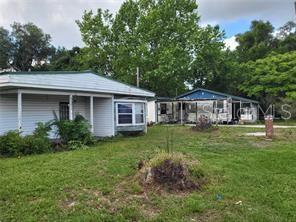 Two light-colored single-story houses sit on a grassy lot surrounded by trees — 5371 WARM SPRINGS AVENUE, WILDWOOD, FL